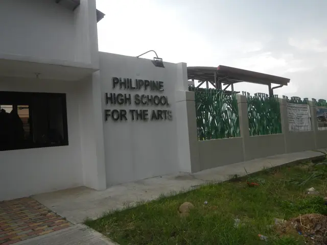 The image shows a building with windows, a wall with text on it, a roof with metal poles, a group...