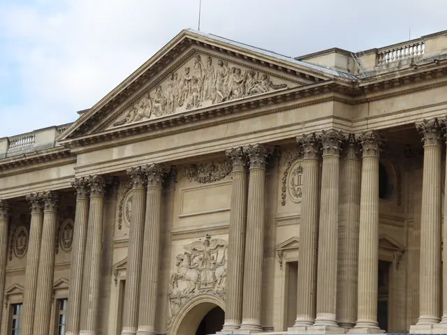 The image shows the British Museum in London, England. It is a large building with windows,...