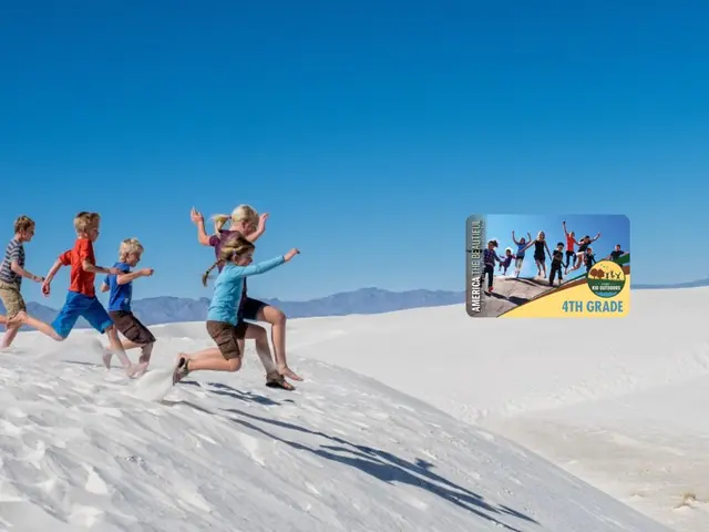 The image shows a group of children running across a white sand dune in Death Valley National Park,...
