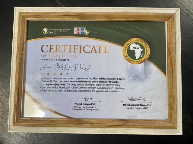 The image shows a certificate of completion placed on a table. The certificate is framed and has...