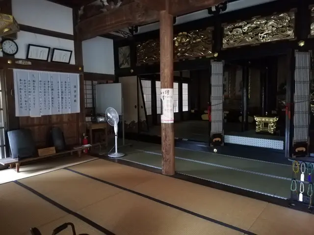 The image shows a room with tatami mats on the floor, a table fan, a chair, a fire extinguisher, a...
