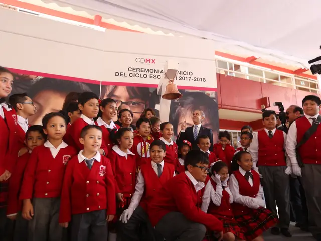 The image shows a group of children in school uniforms standing in front of a crowd of people, some...