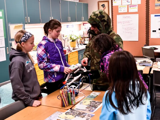 The image shows a group of students gathered around a table in a classroom. On the table there are...