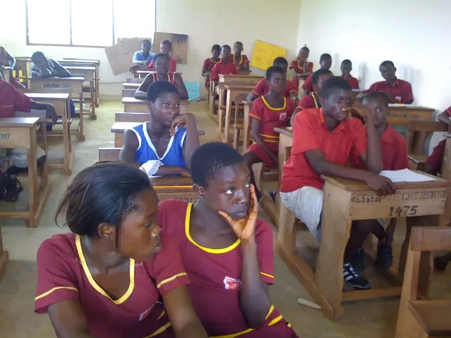 The image shows a group of children sitting at desks in a classroom, with books and other objects...