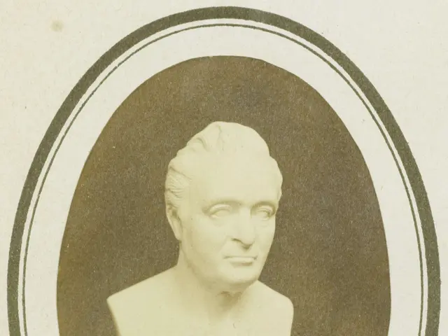 The image shows a black and white photo of a bust of a man with a human face. The man has a serious...