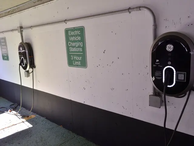 The image shows an electric vehicle charging station in a parking garage, with two charging...