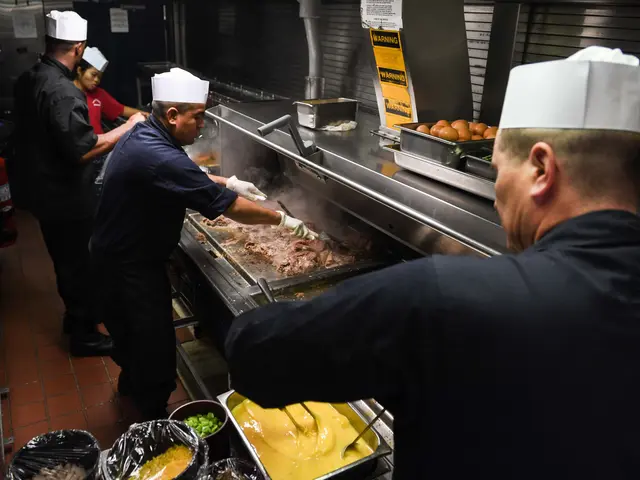 The image shows a group of four chefs in a kitchen preparing food on a grill. They are wearing...