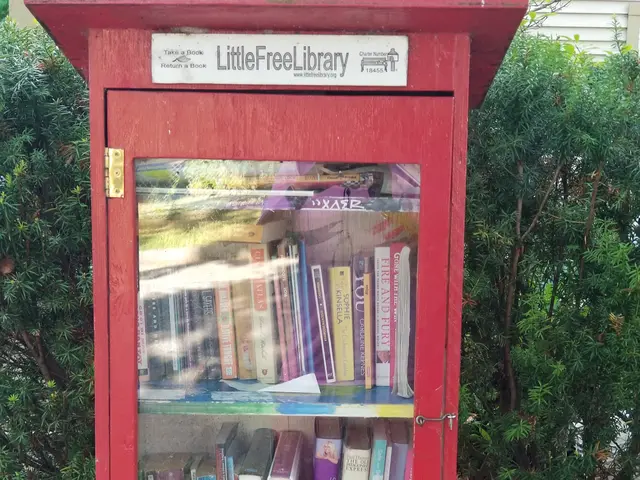The image shows a red box filled with books sitting on top of a tree, with a white board attached...