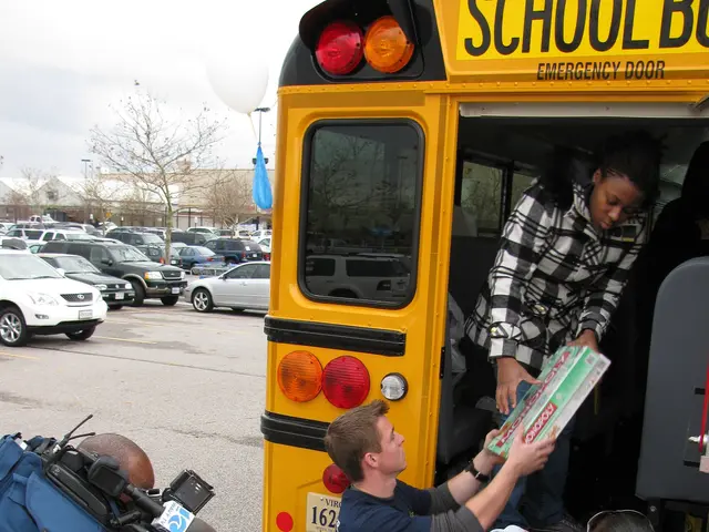 The image shows a group of people standing in front of a school bus. The person in the front is...