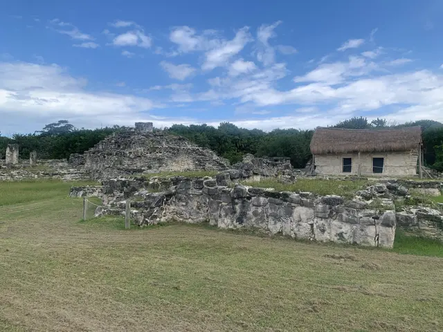 The image shows the ruins of the Mayan city of Tikalpa, Guatemala, with a grassy land in the...